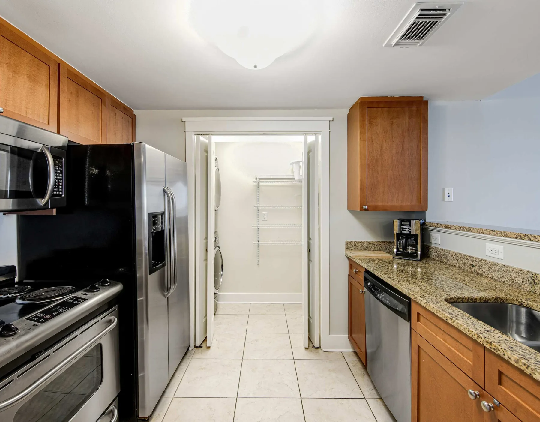 A kitchen with stainless steel appliances and a countertop beside an open pantry.