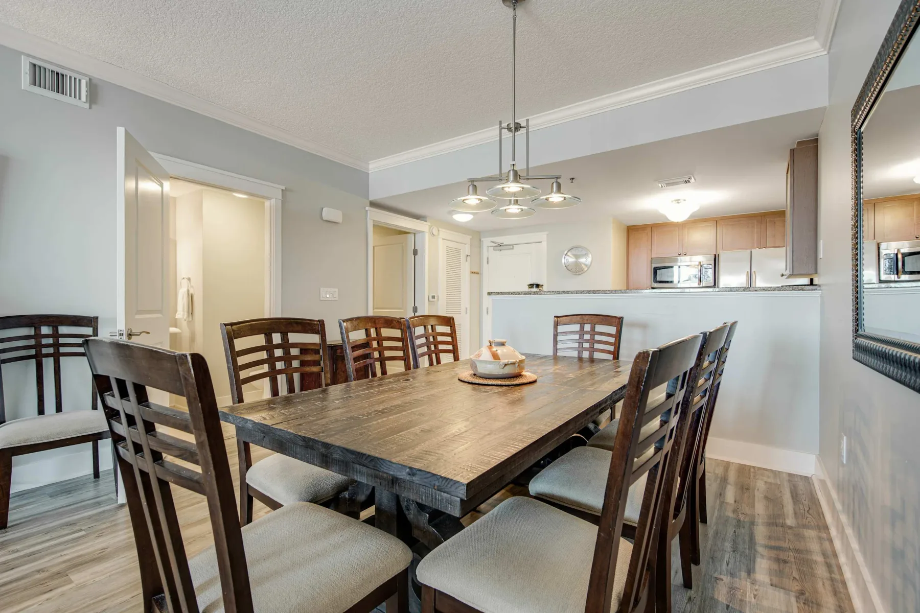 A dining area with a wooden table and chairs beneath a hanging light.