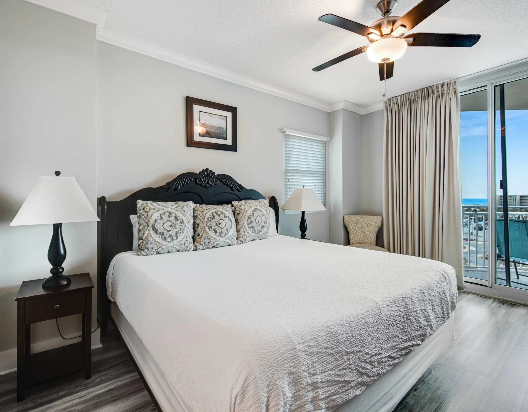 A bedroom with a large bed, bedside tables, and a sliding glass door.