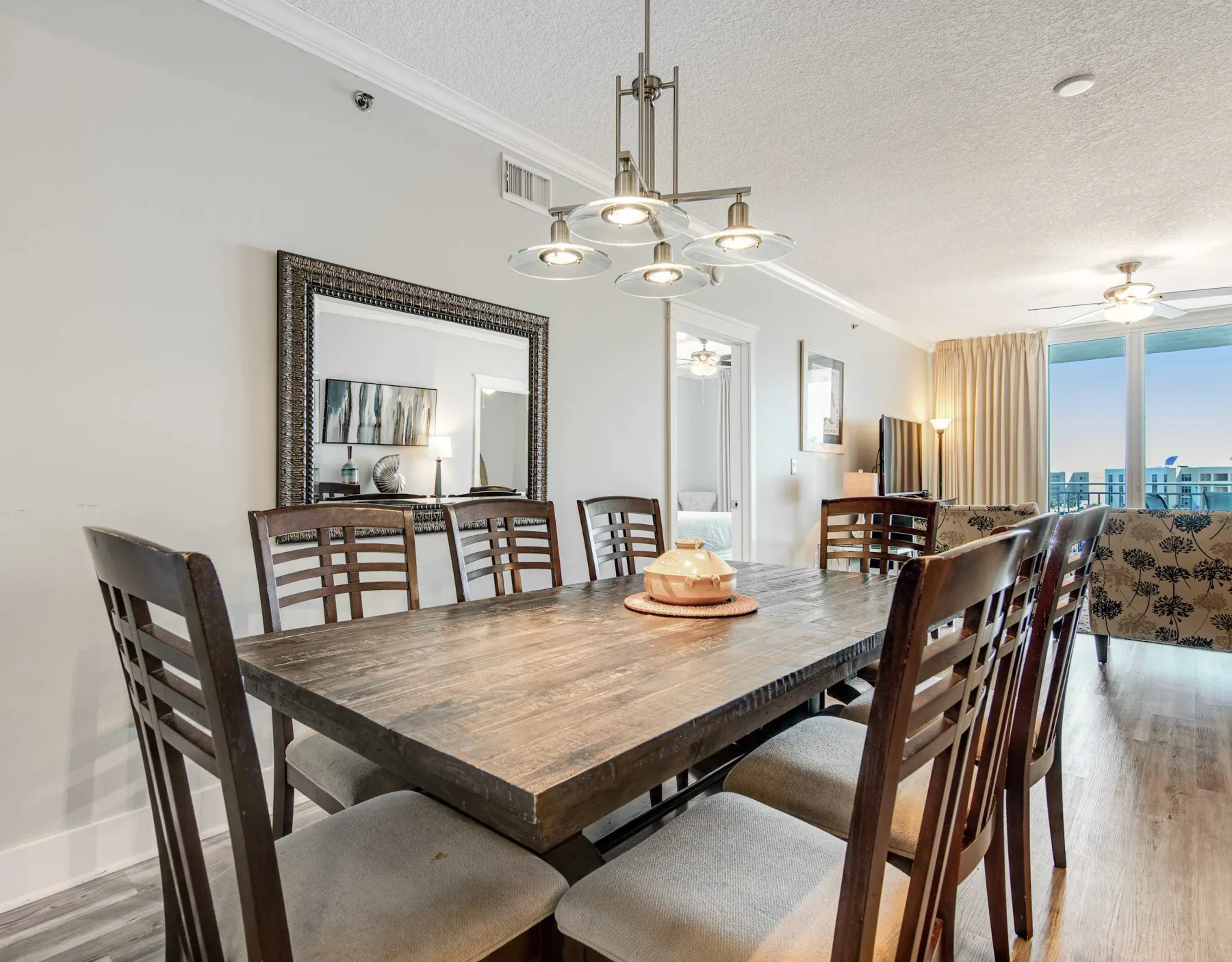 A dining room with a long table and chairs beneath a chandelier.