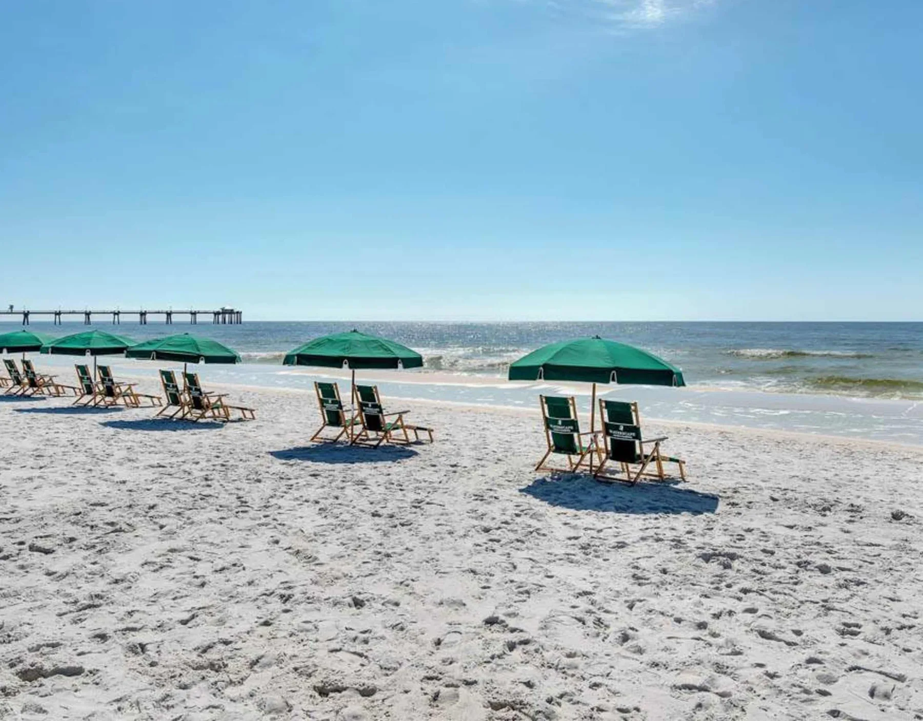 Shared amenity: A sandy beach with green umbrellas and seating facing the ocean.