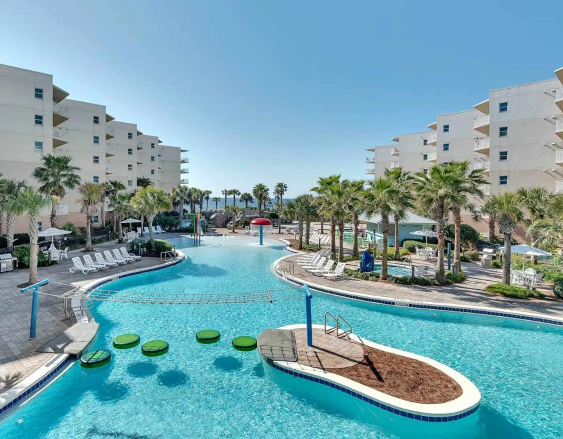 Shared amenity: A resort-style swimming pool winds between palm trees and white buildings.