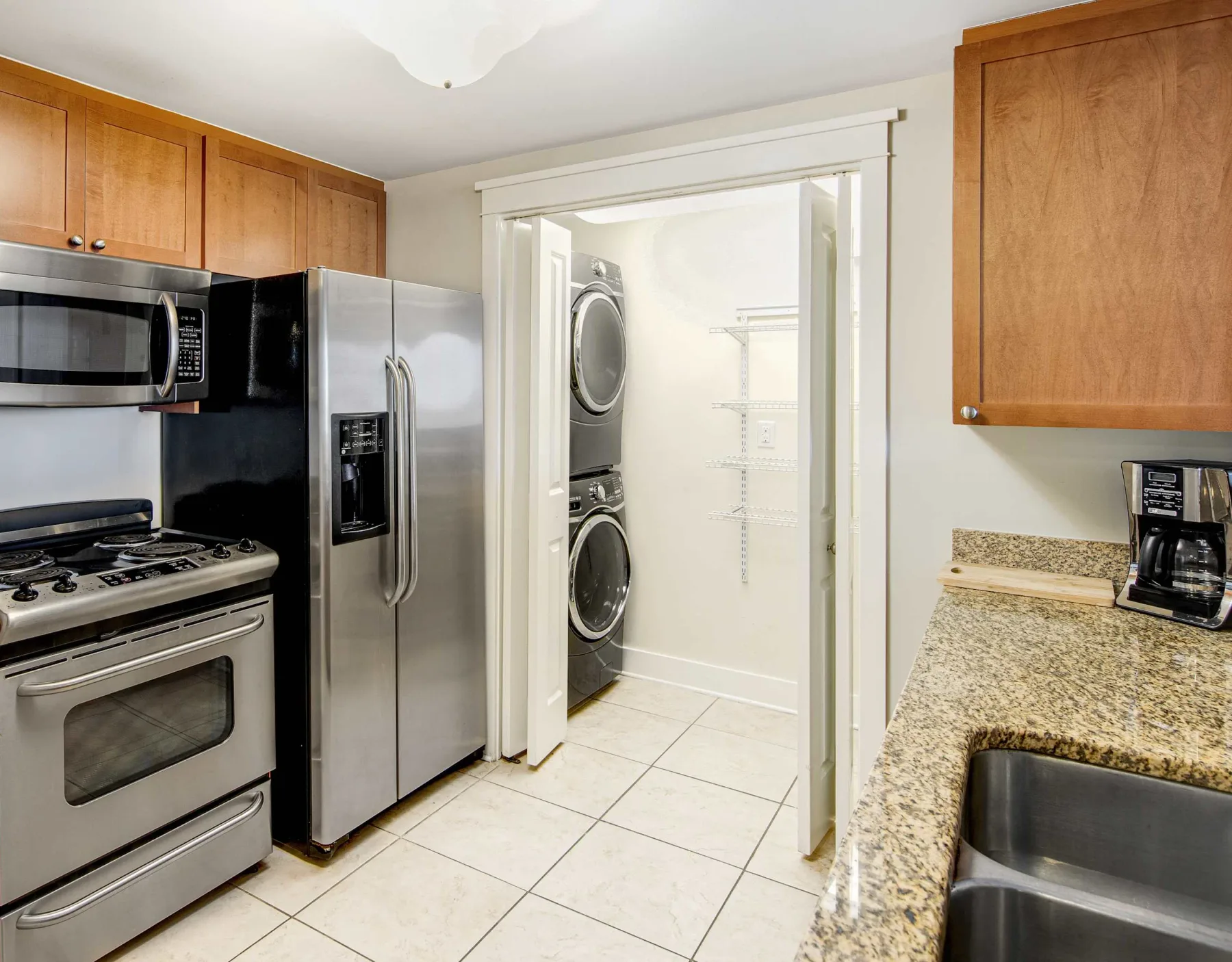 A kitchen with stainless steel appliances and a laundry area visible through the doorway.