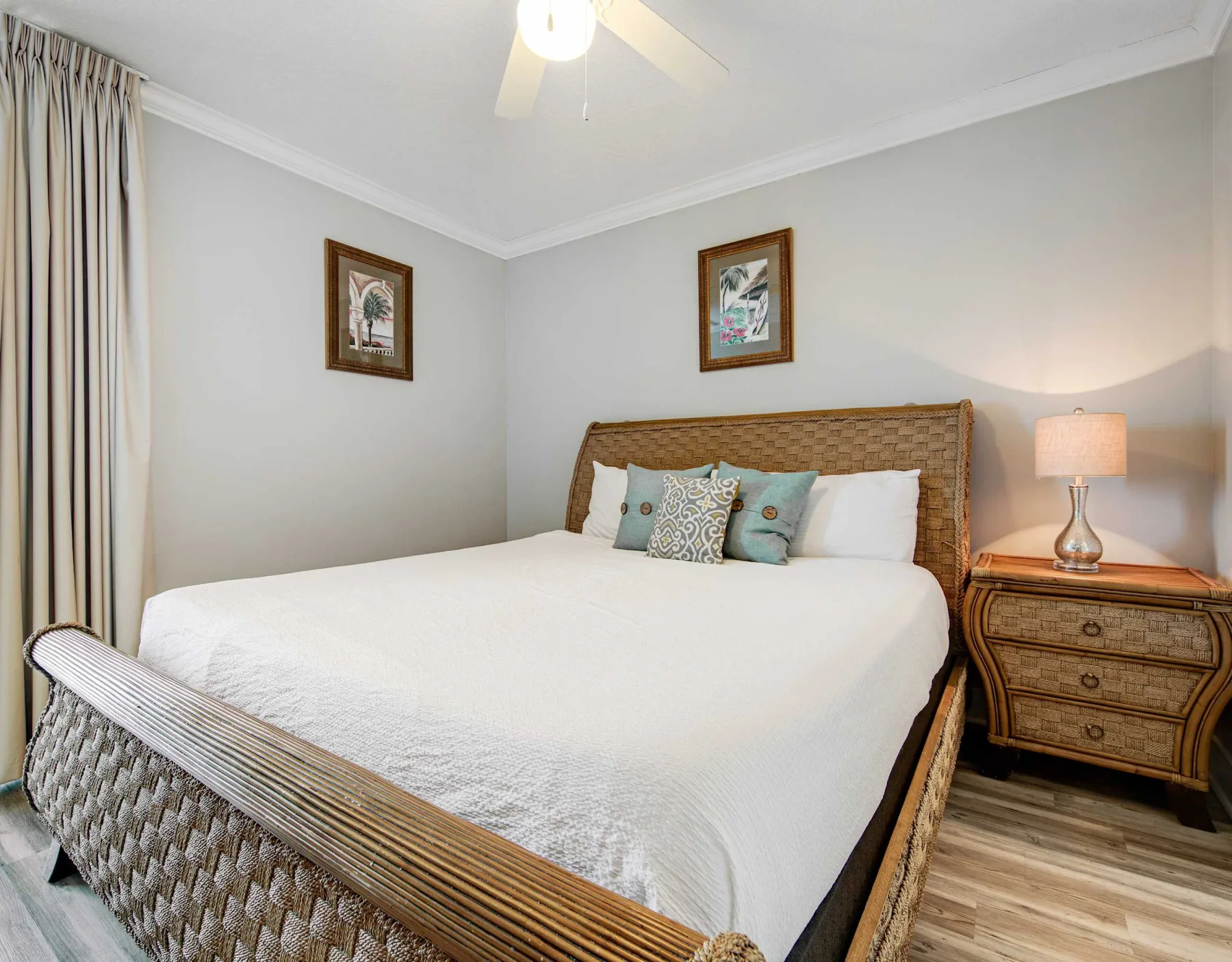 A bedroom with a neatly made bed and a bedside table with a lamp.