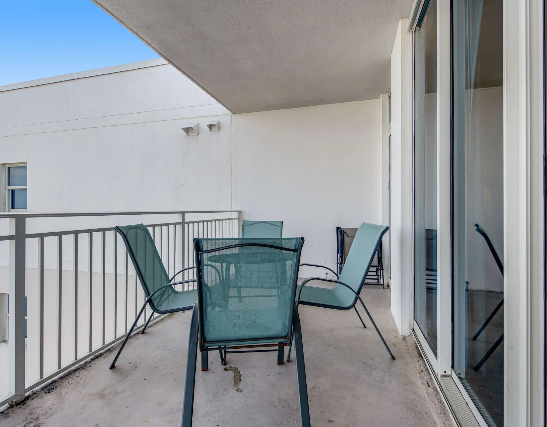 A balcony with outdoor seating and sliding glass doors.
