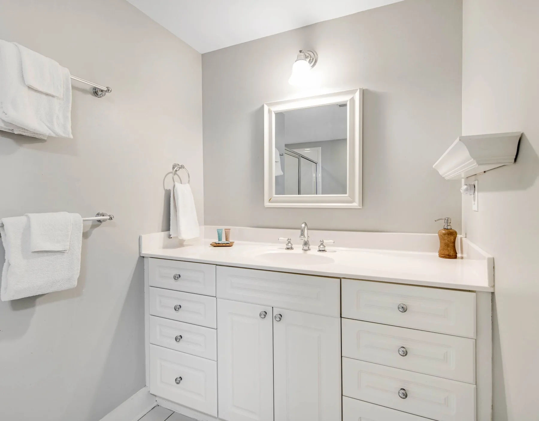 A bright bathroom with a wide vanity, sink, and mirror.