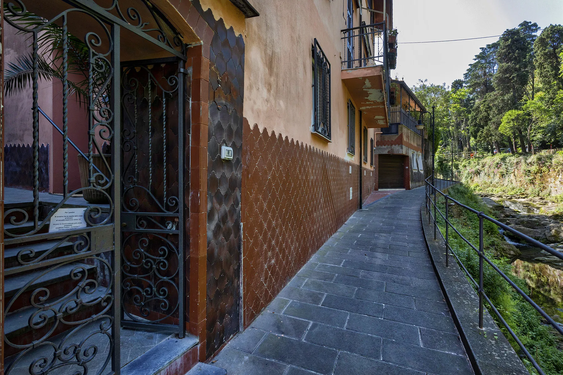 Shared amenity: A paved outdoor walkway runs alongside a building and a wooded stream.