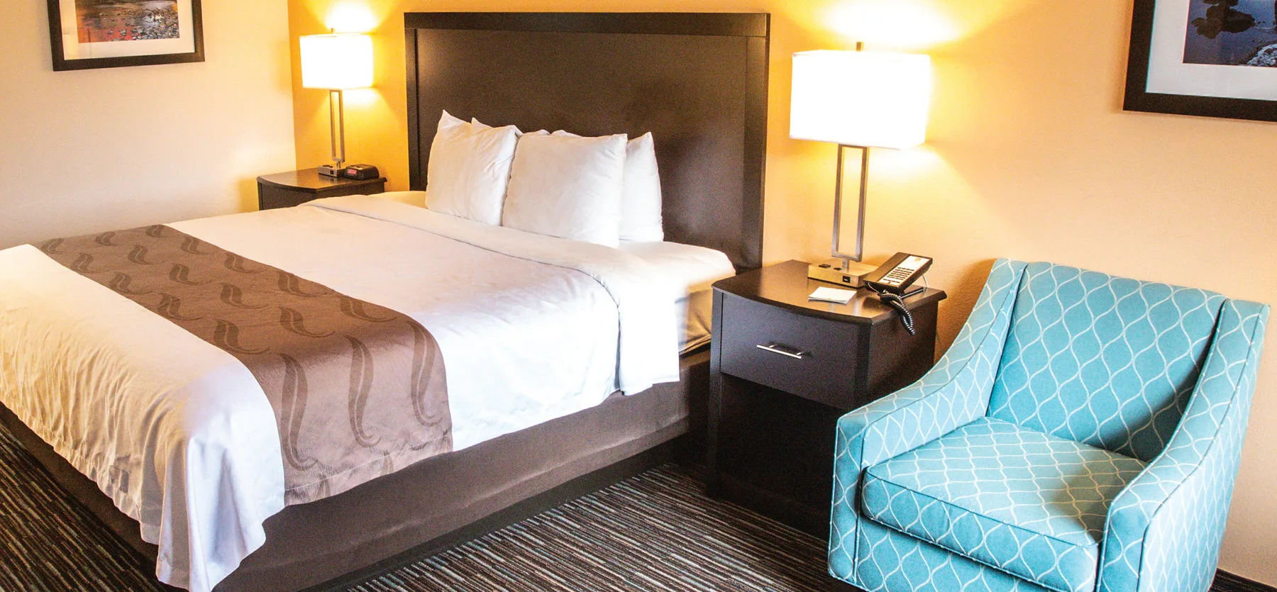 Representative hotel space: A hotel bedroom with a neatly made bed and a blue upholstered chair.