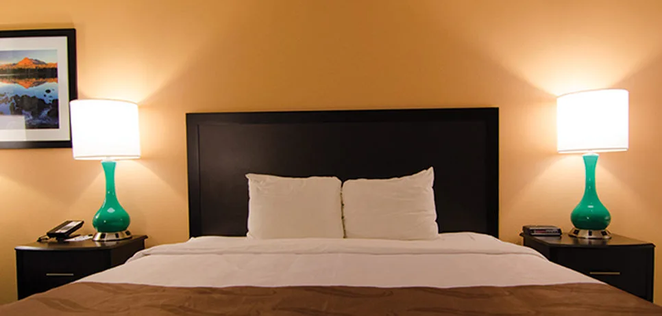 Representative hotel space: A bedroom with a bed, dark headboard, and matching bedside lamps.