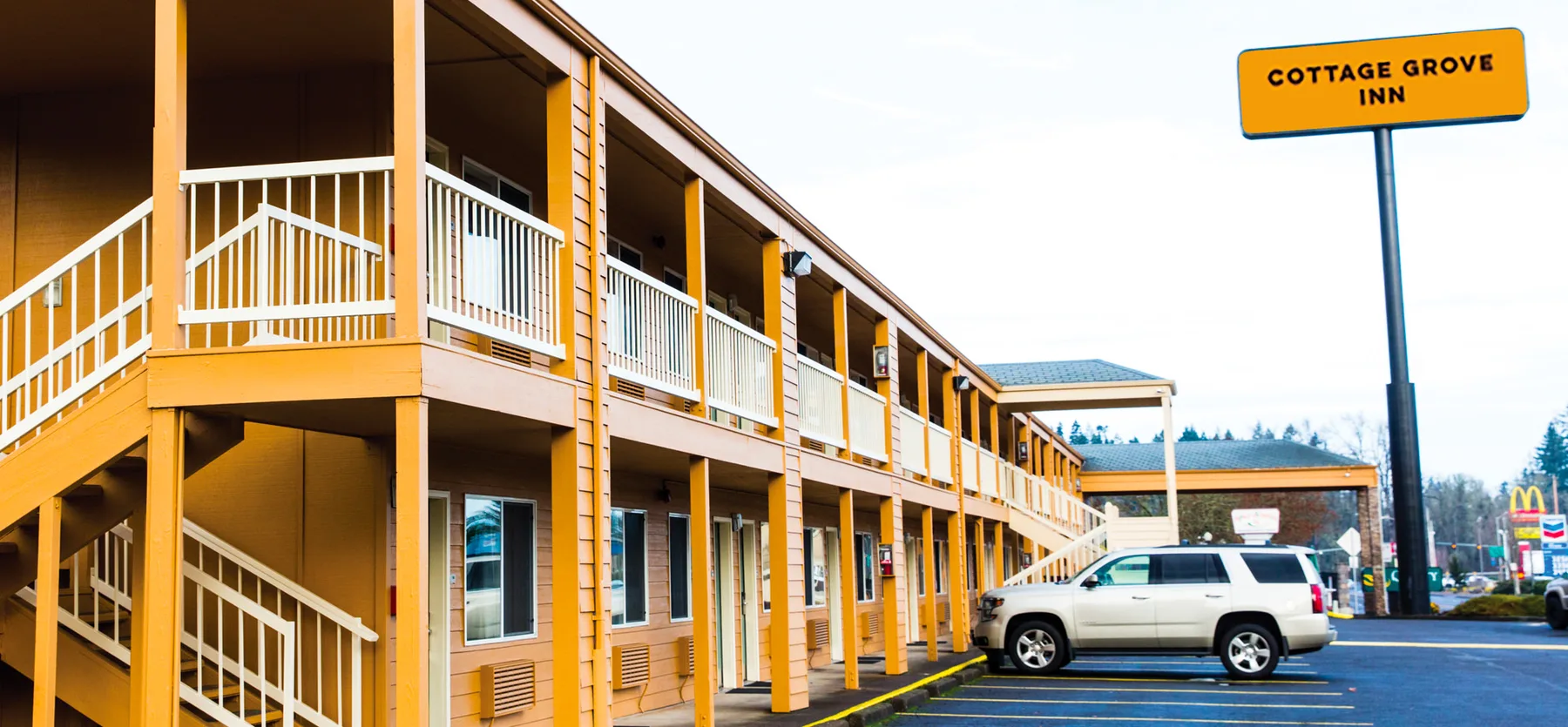 Representative hotel space: A two-story inn exterior with open walkways and a parked vehicle.