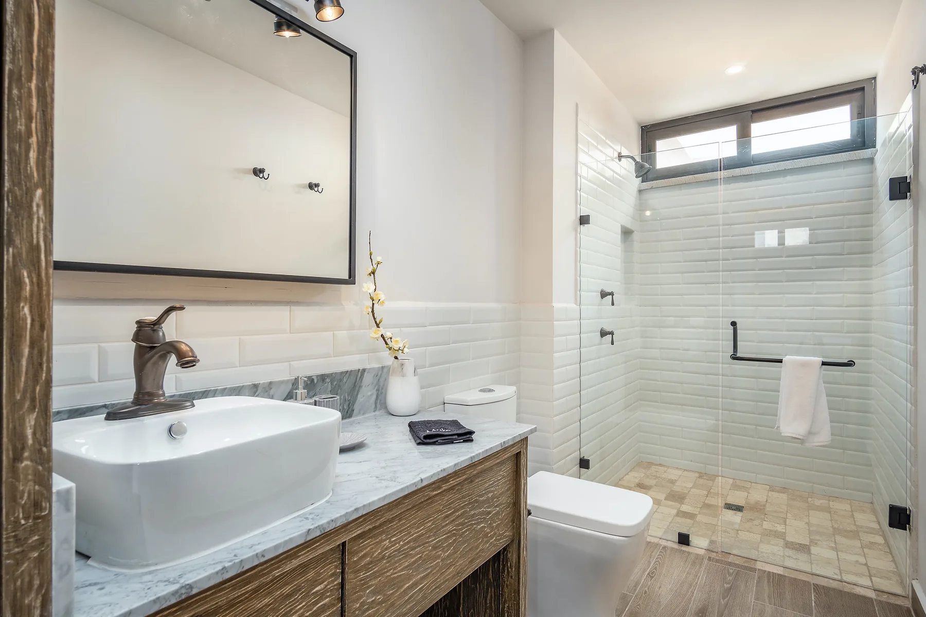 Un baño con lavabo y ducha con mampara de vidrio.