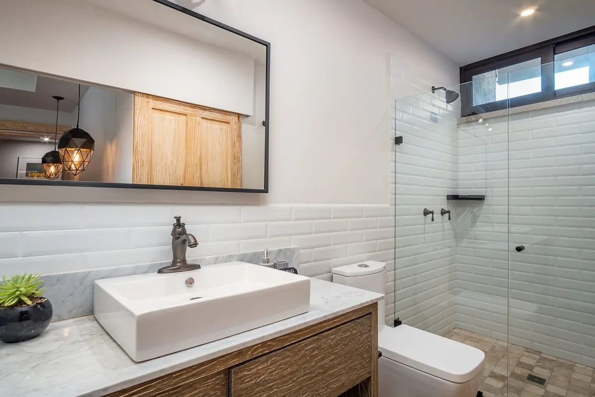 Un baño con lavabo sobre encimera y una ducha de vidrio.