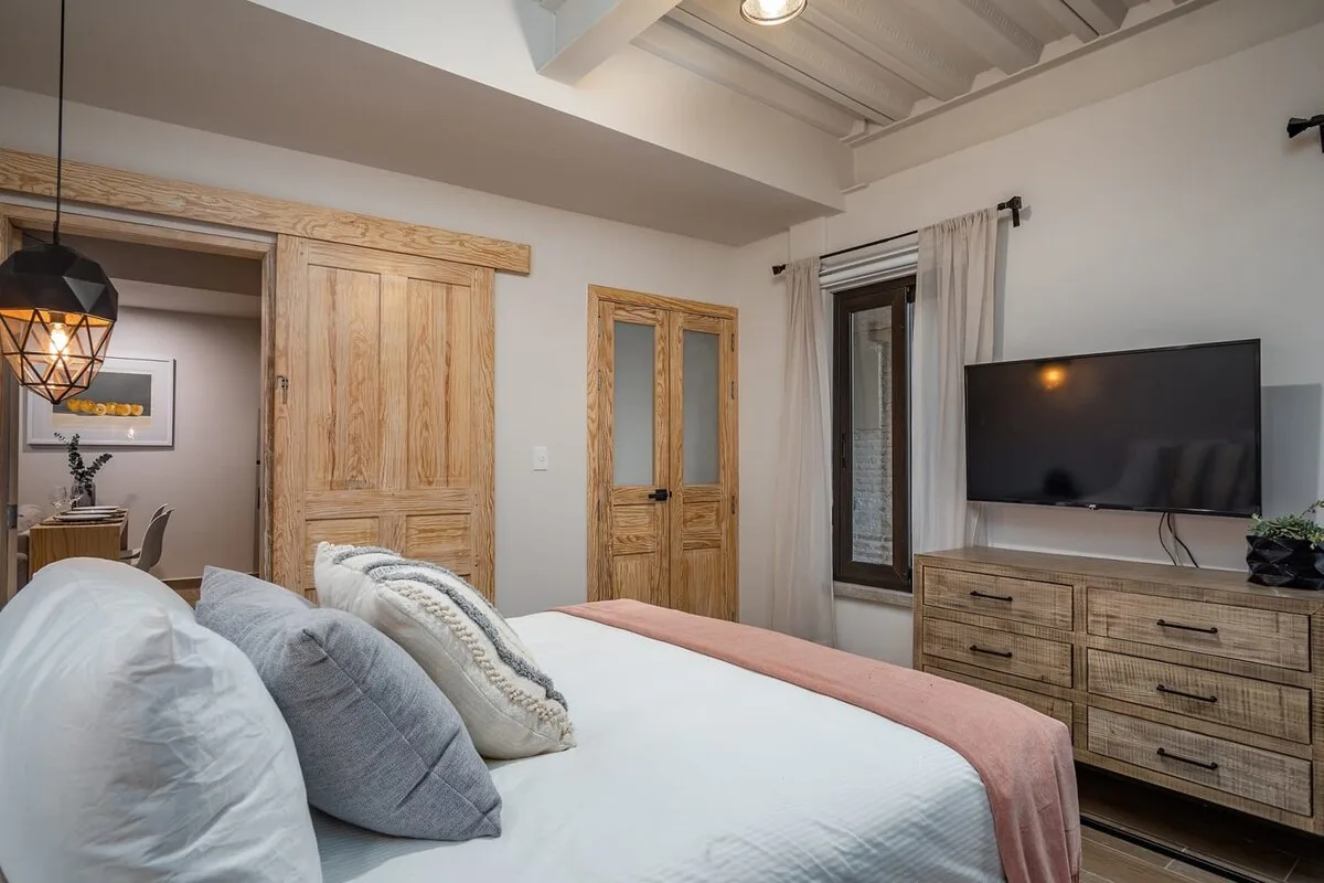 Un dormitorio con una cama, puertas de madera y un televisor sobre una cómoda.