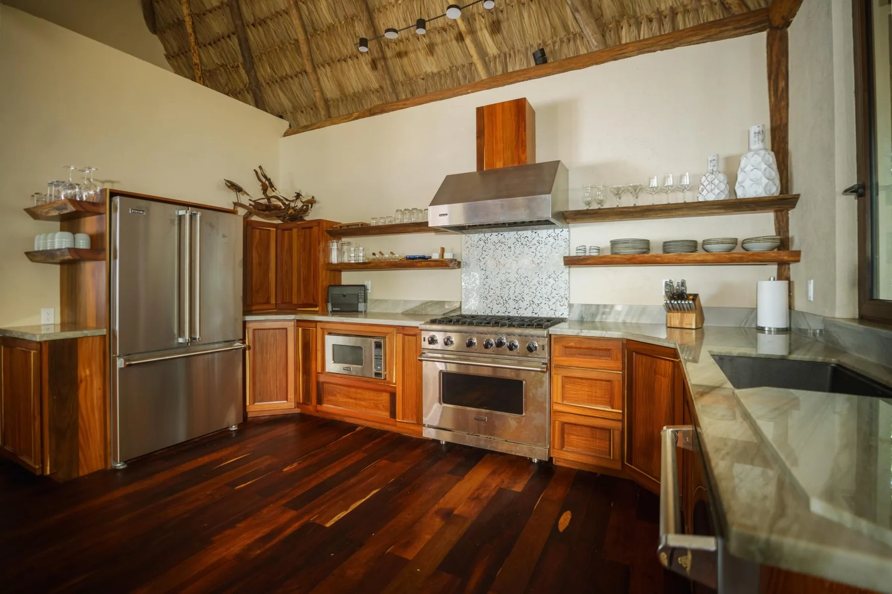 A spacious kitchen with wooden cabinets, stainless steel appliances, and a dark wood floor.