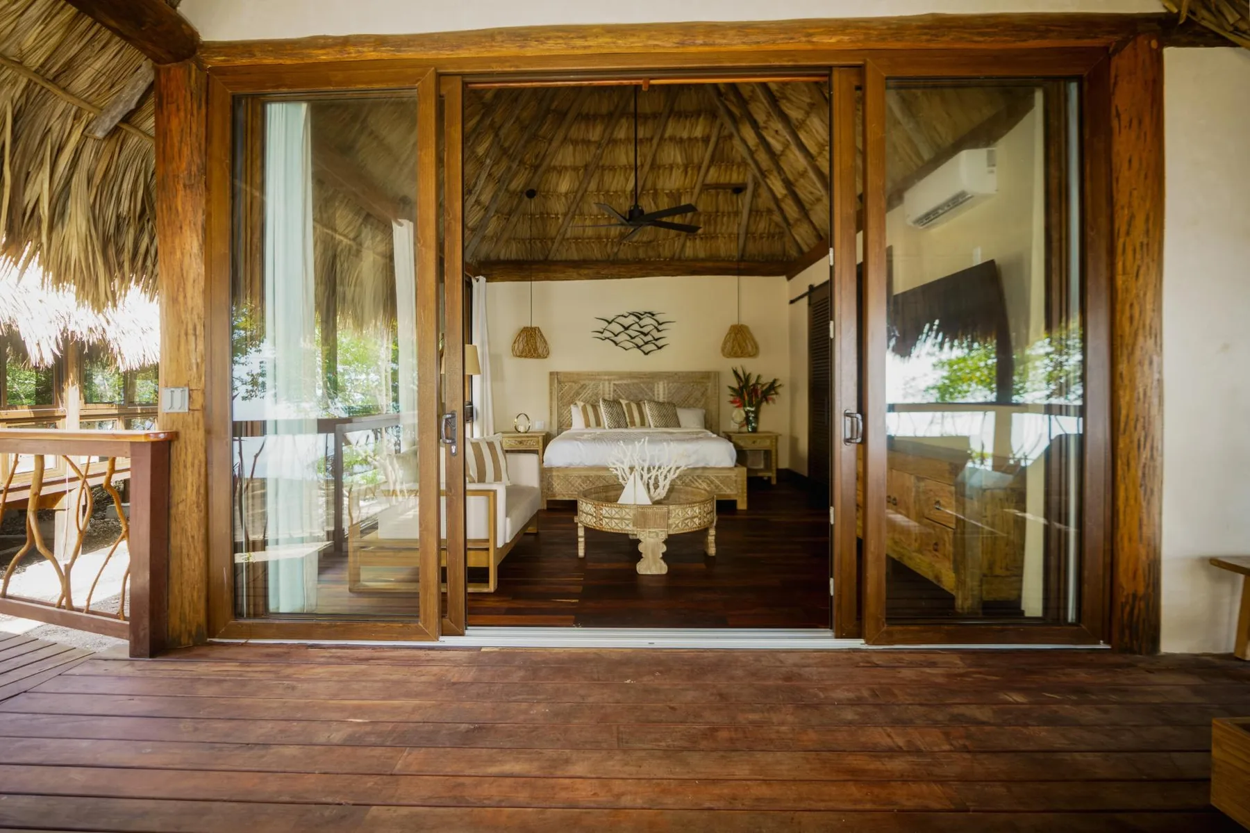 A bedroom with a bed is visible through open wooden-framed glass doors.