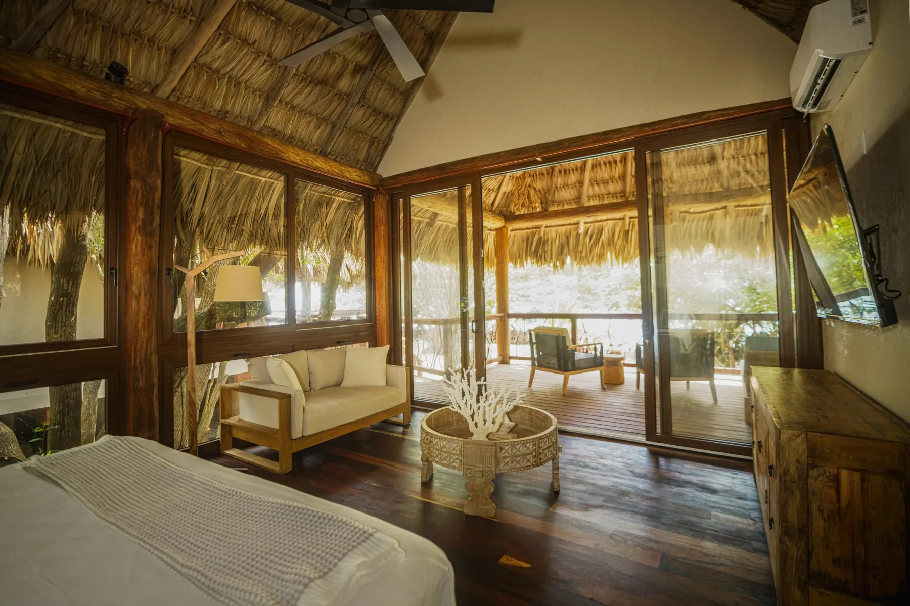 A bedroom with a bed and seating beside glass doors opening onto a covered patio.