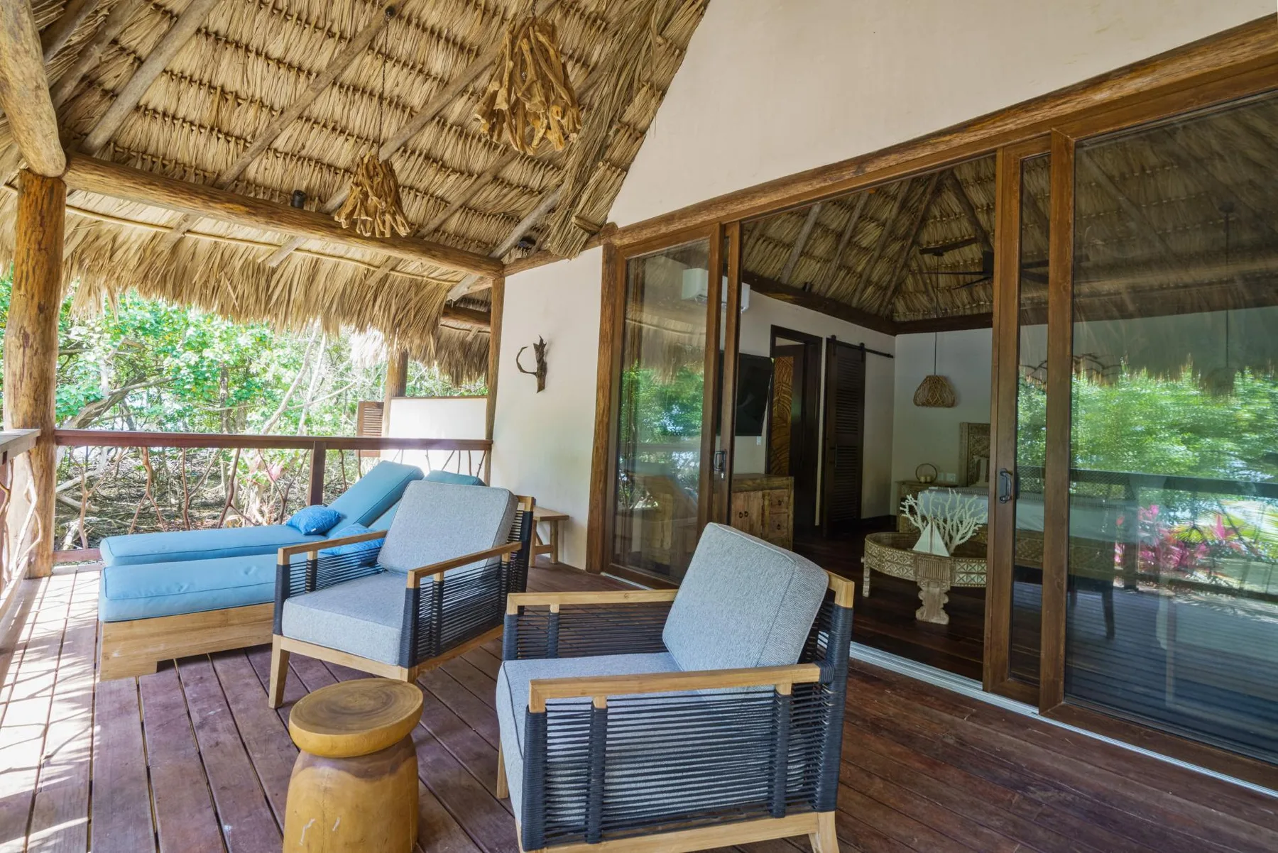 A covered outdoor seating area with a thatched roof and sliding glass doors.