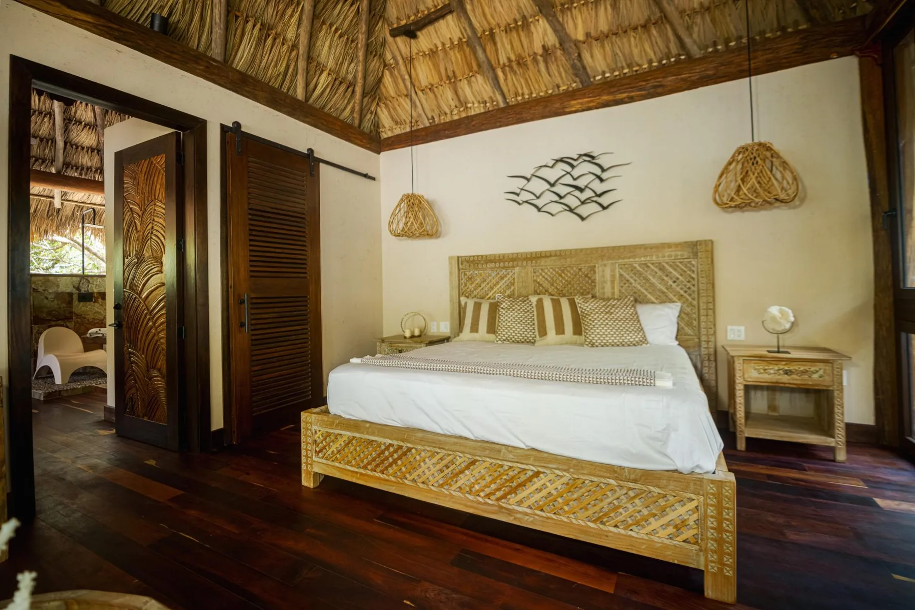 A bedroom with a woven bed frame and a high thatched ceiling.