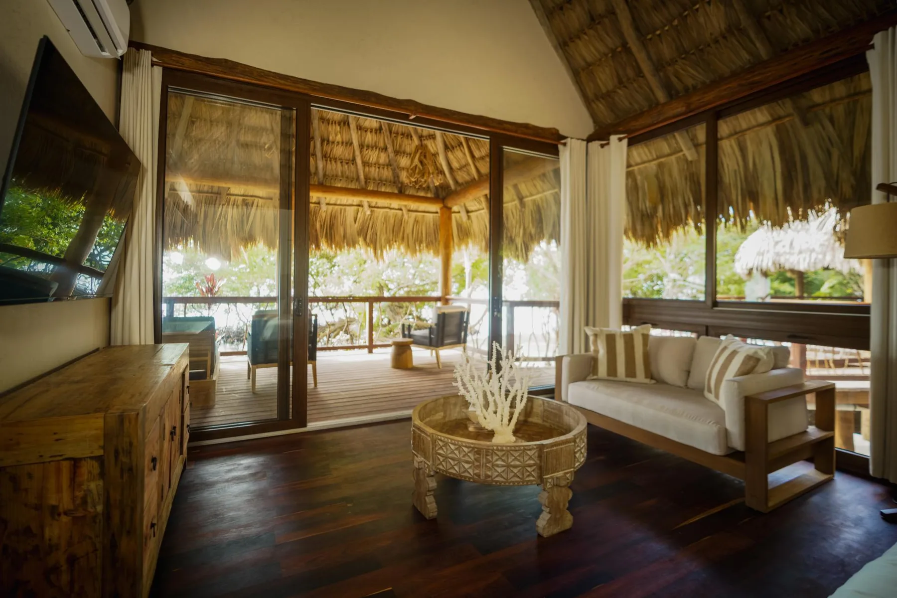 An open lounge with seating and a round table overlooks a covered deck.