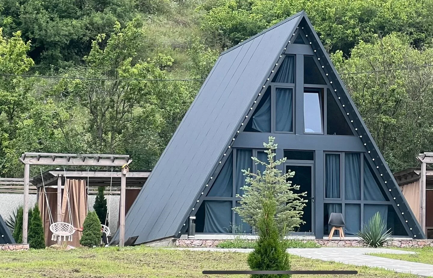 Espacio representativo del hotel: Cabaña en forma de A con grandes ventanas y árboles al fondo.