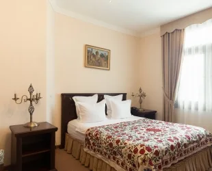 Representative hotel space: A bedroom with a bed, patterned bedding, and a window with curtains.