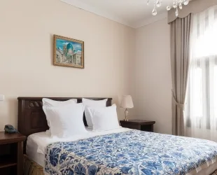 Representative hotel space: A bedroom with a double bed, patterned bedding, and a curtained window.