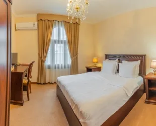 Representative hotel space: A bedroom with a large bed, bedside tables, and a curtained window.