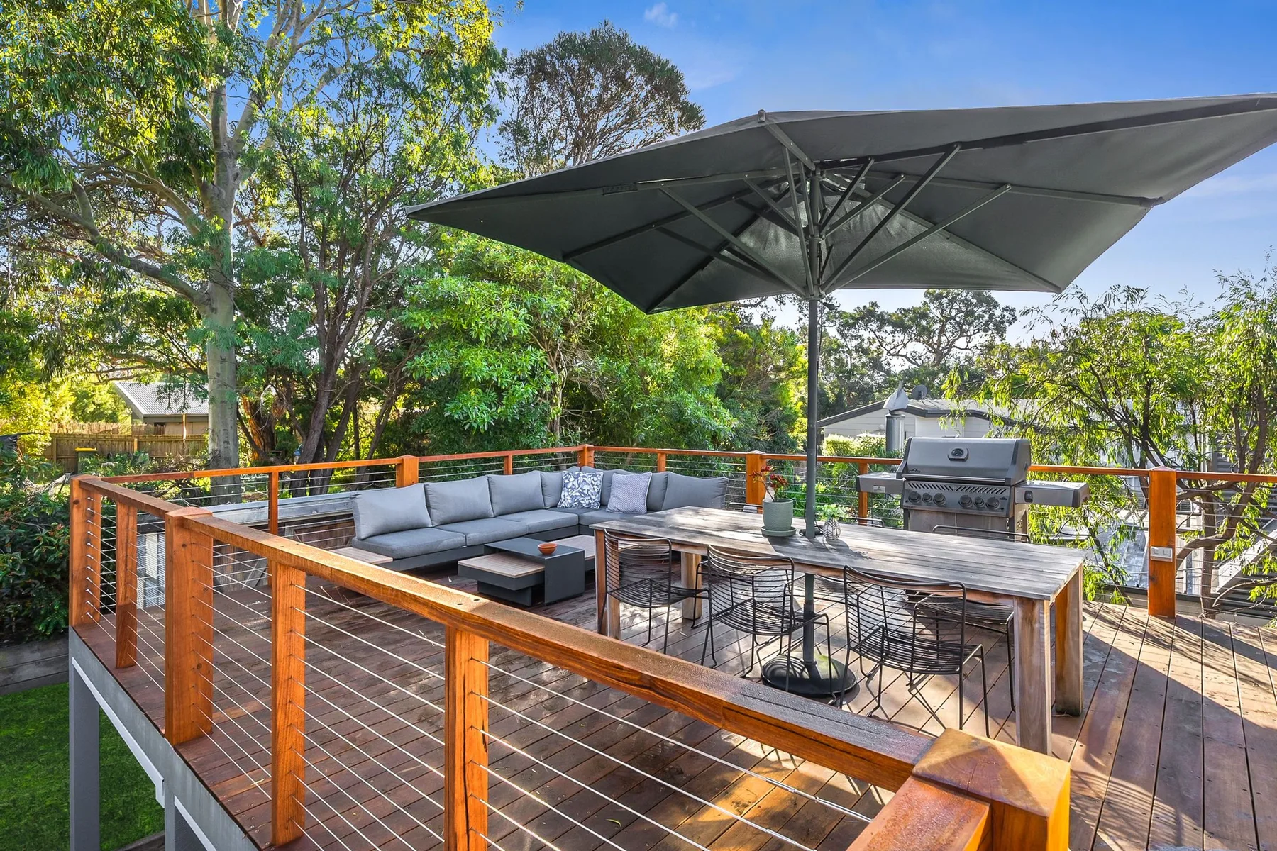 Una terraza exterior con asientos, una mesa de comedor y una sombrilla grande.