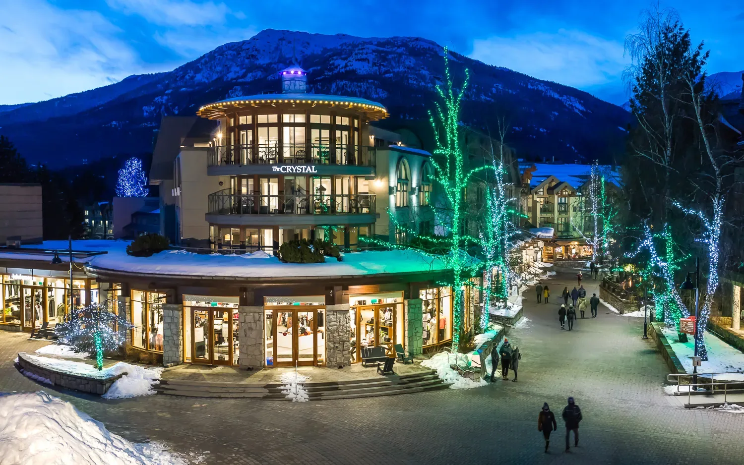 Representative hotel space: A hotel building and pedestrian walkway are illuminated by decorative lights at dusk.