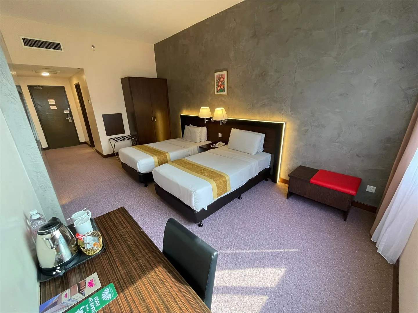Representative hotel space: A hotel bedroom with two beds, a desk, and a dark accent wall.