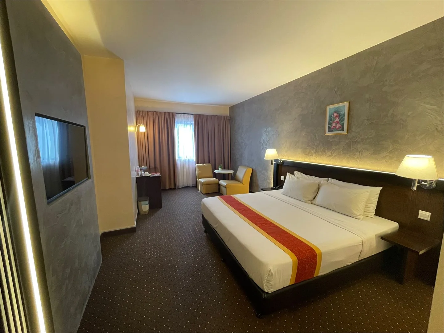 Representative hotel space: Hotel bedroom with a large bed and a small seating area by the window.