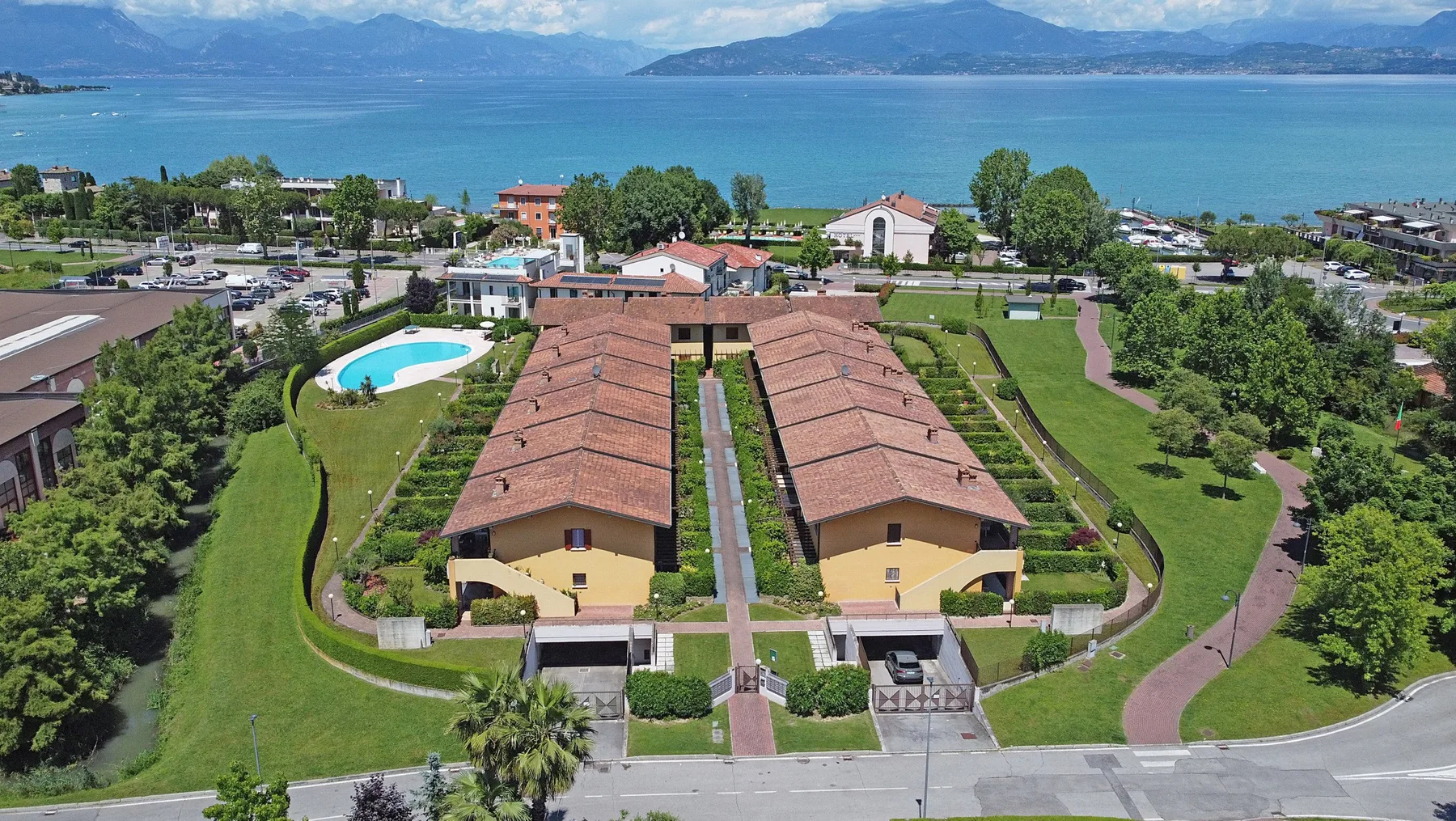 Zona común: Vista aérea de un complejo junto al lago con edificios alineados y una piscina.