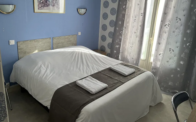 Representative hotel space: A bedroom with a neatly made bed beside a window.