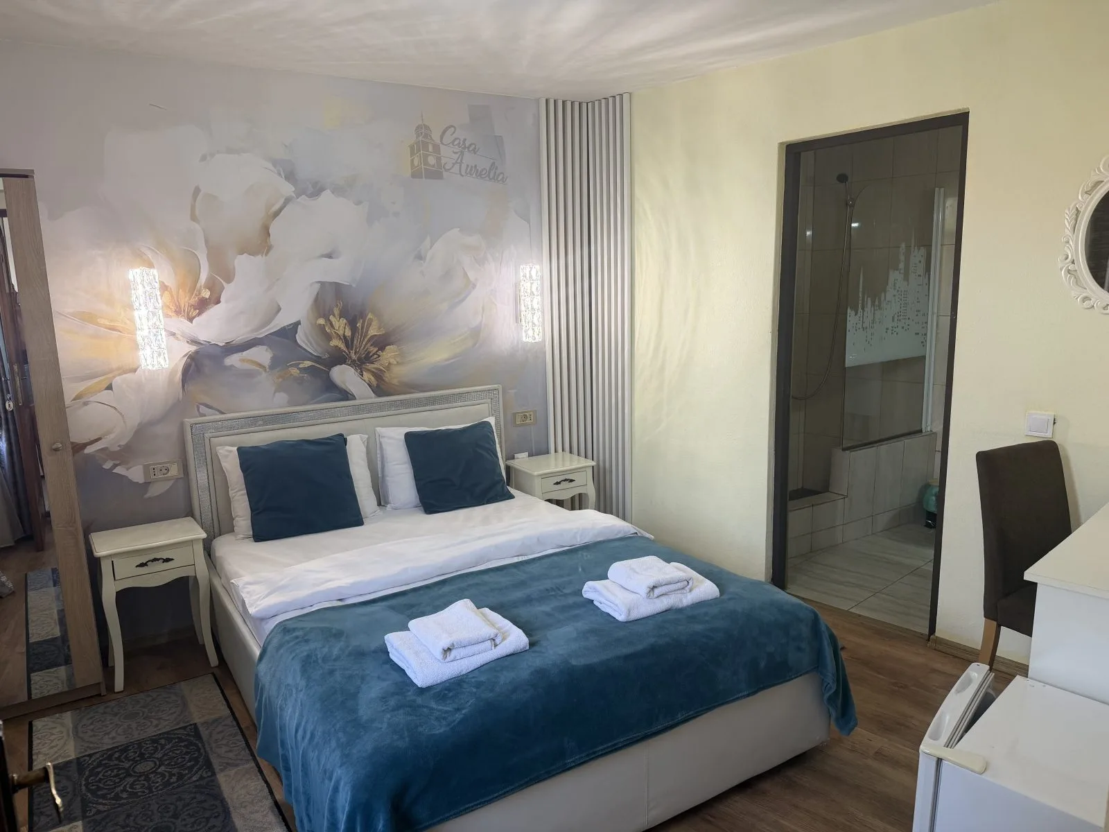 Representative hotel space: A bedroom with a bed, blue bedding, and floral wall art.