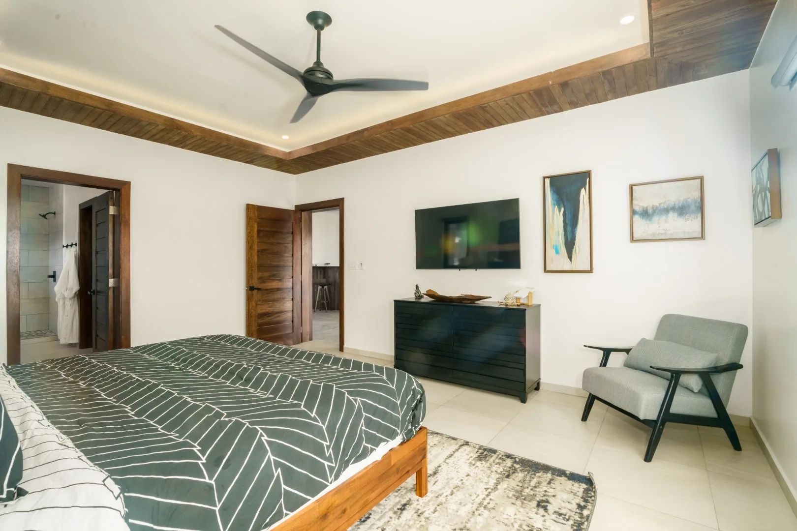 A bedroom with a bed, wall-mounted television, and seating.