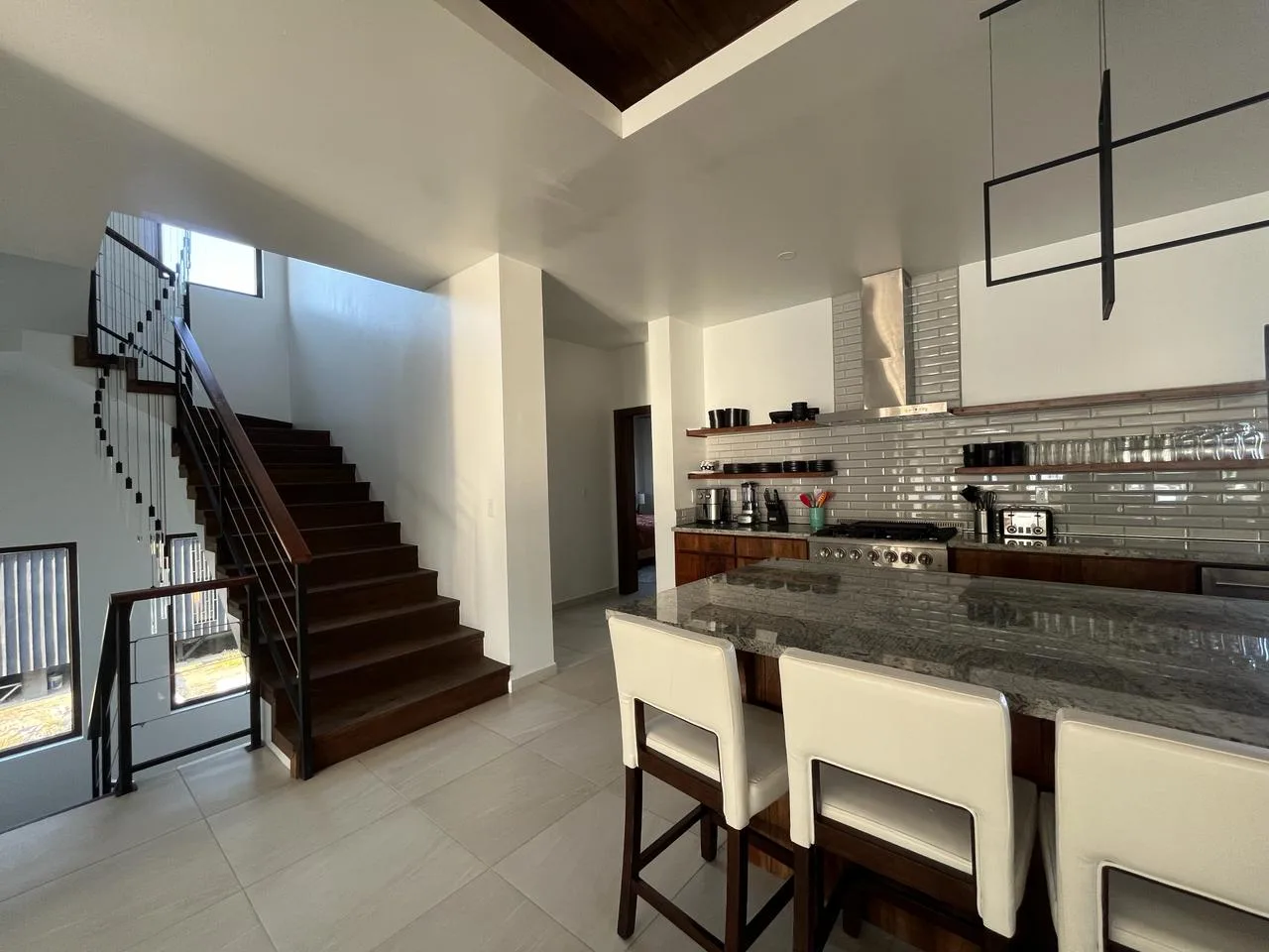 An open kitchen and dining area with a broad island beside a staircase.