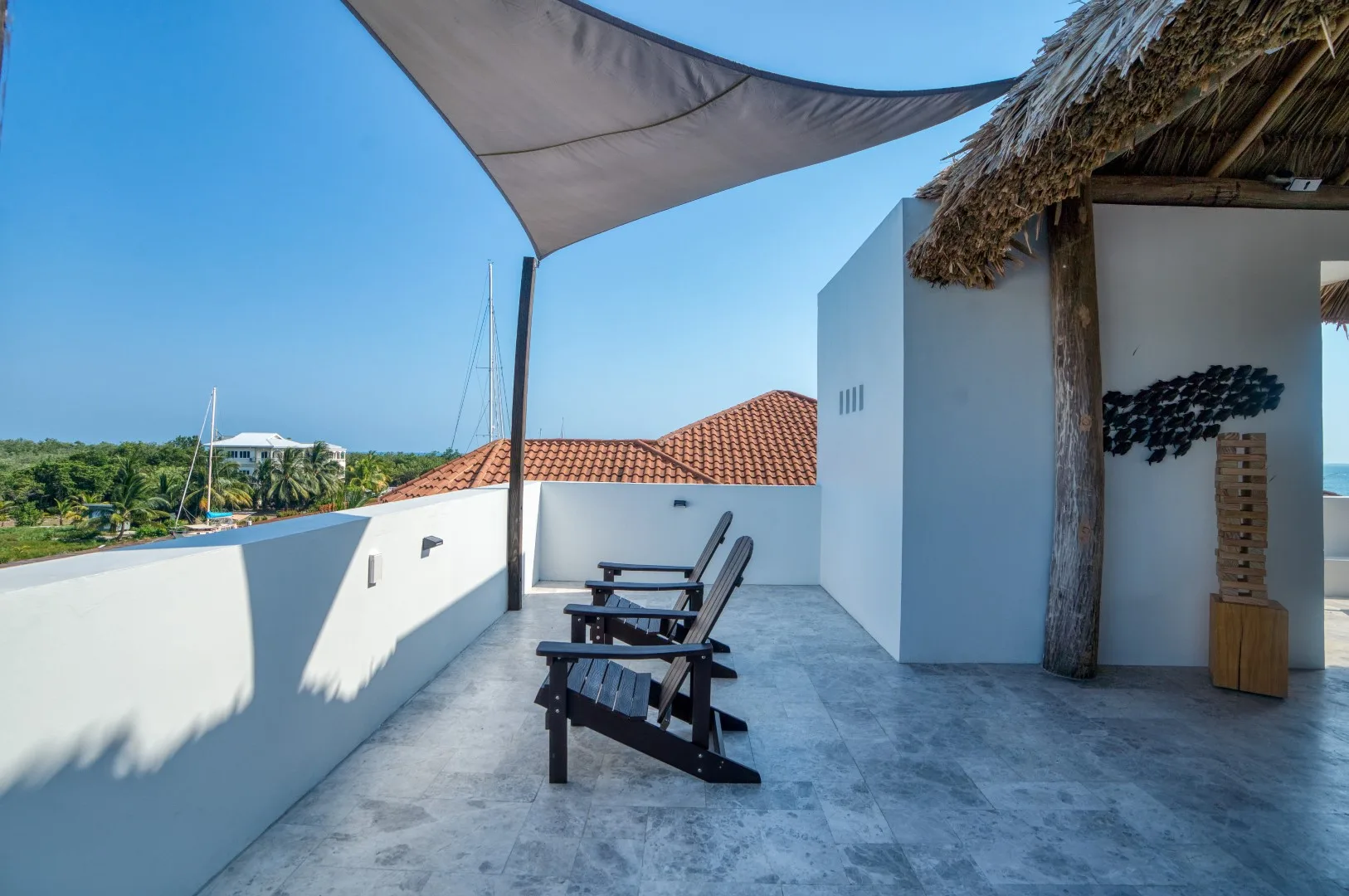 A rooftop terrace has lounge seating beneath a shade canopy.
