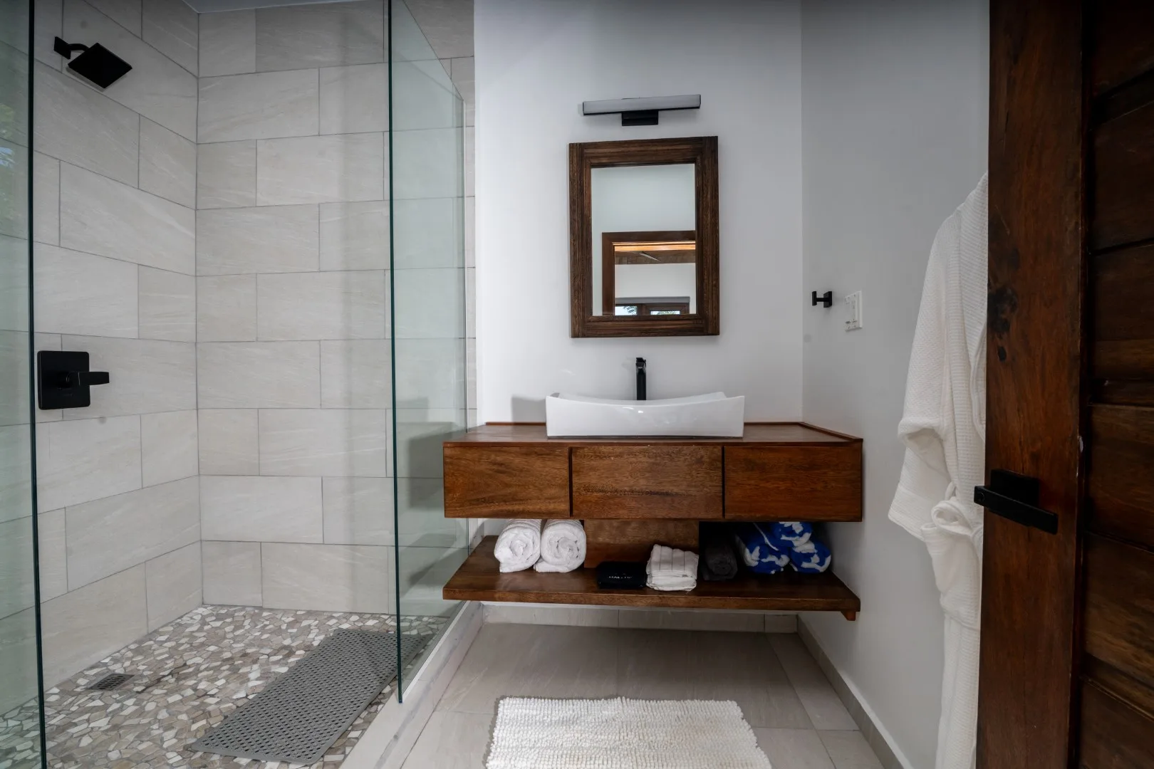 A modern bathroom with a glass shower and a wooden vanity.