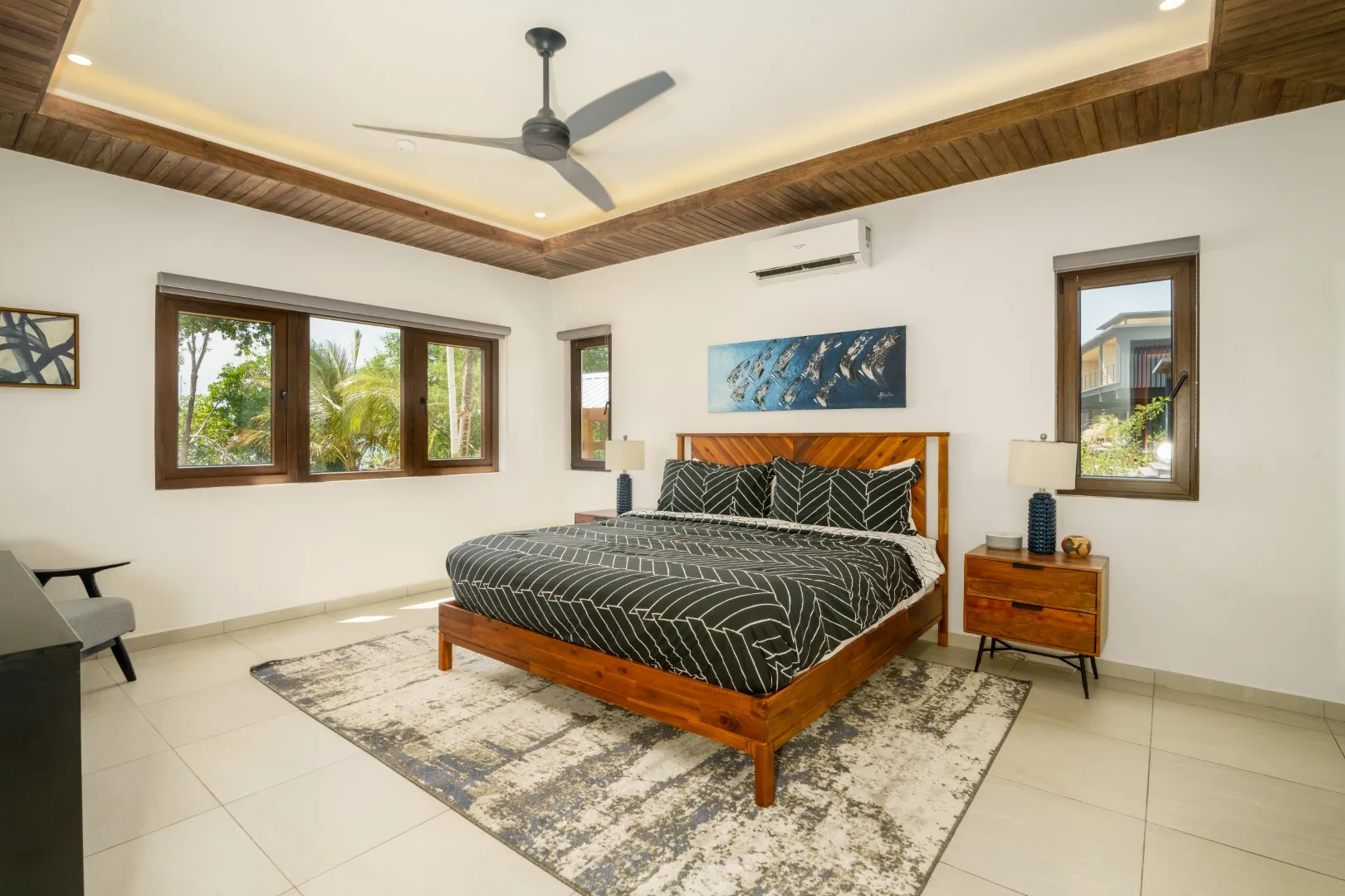 A bedroom with a bed, windows, and a ceiling fan.