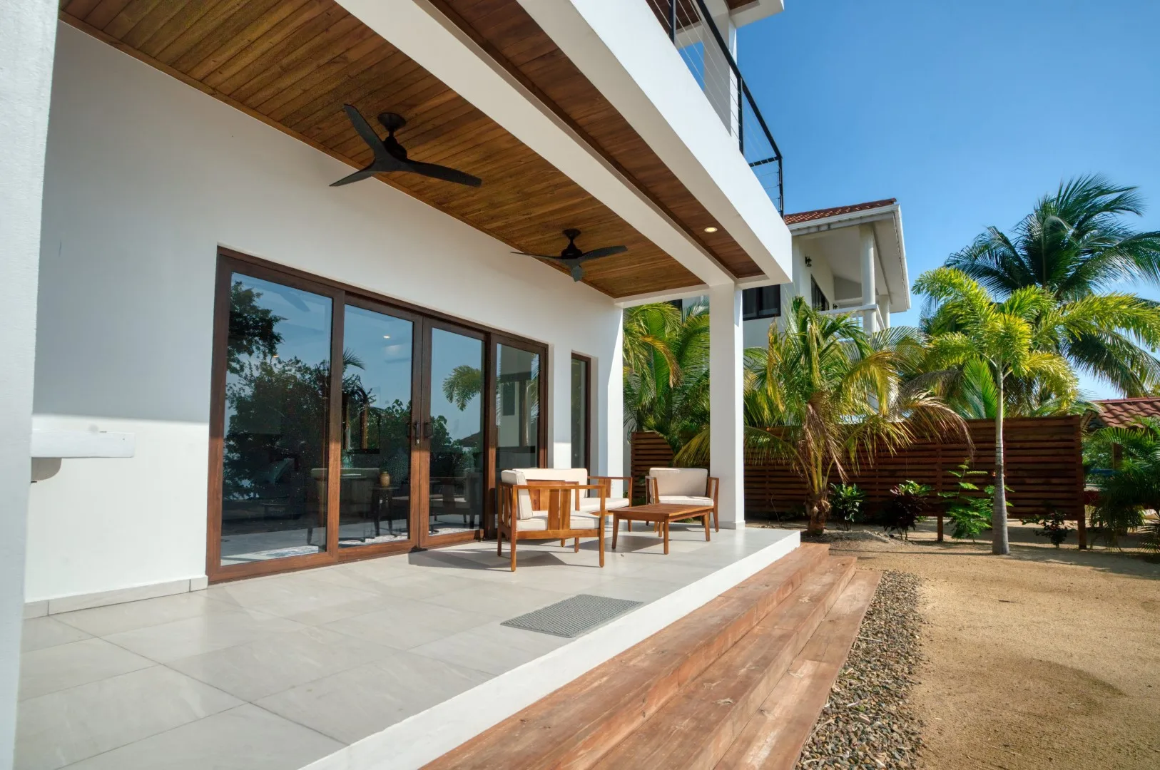 A modern home opens onto a tiled patio with sliding glass doors.