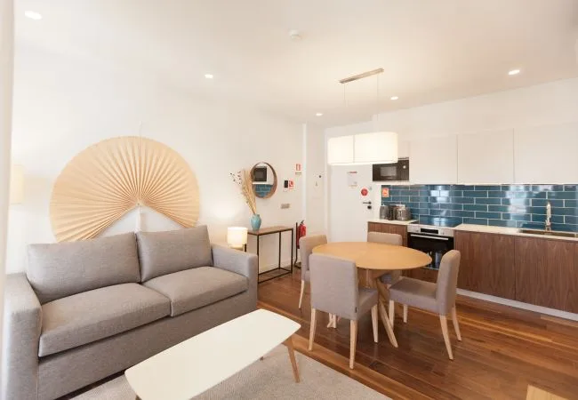 A living and dining area opens onto a kitchen with dark tile backsplash.