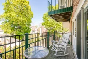 Representative hotel space: A balcony with outdoor seating overlooks leafy trees and neighboring buildings.