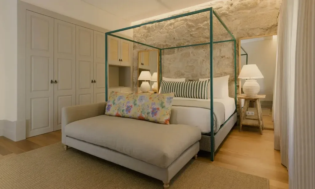 Espacio representativo del hotel: Dormitorio con cama con dosel, asiento tapizado y armarios empotrados.