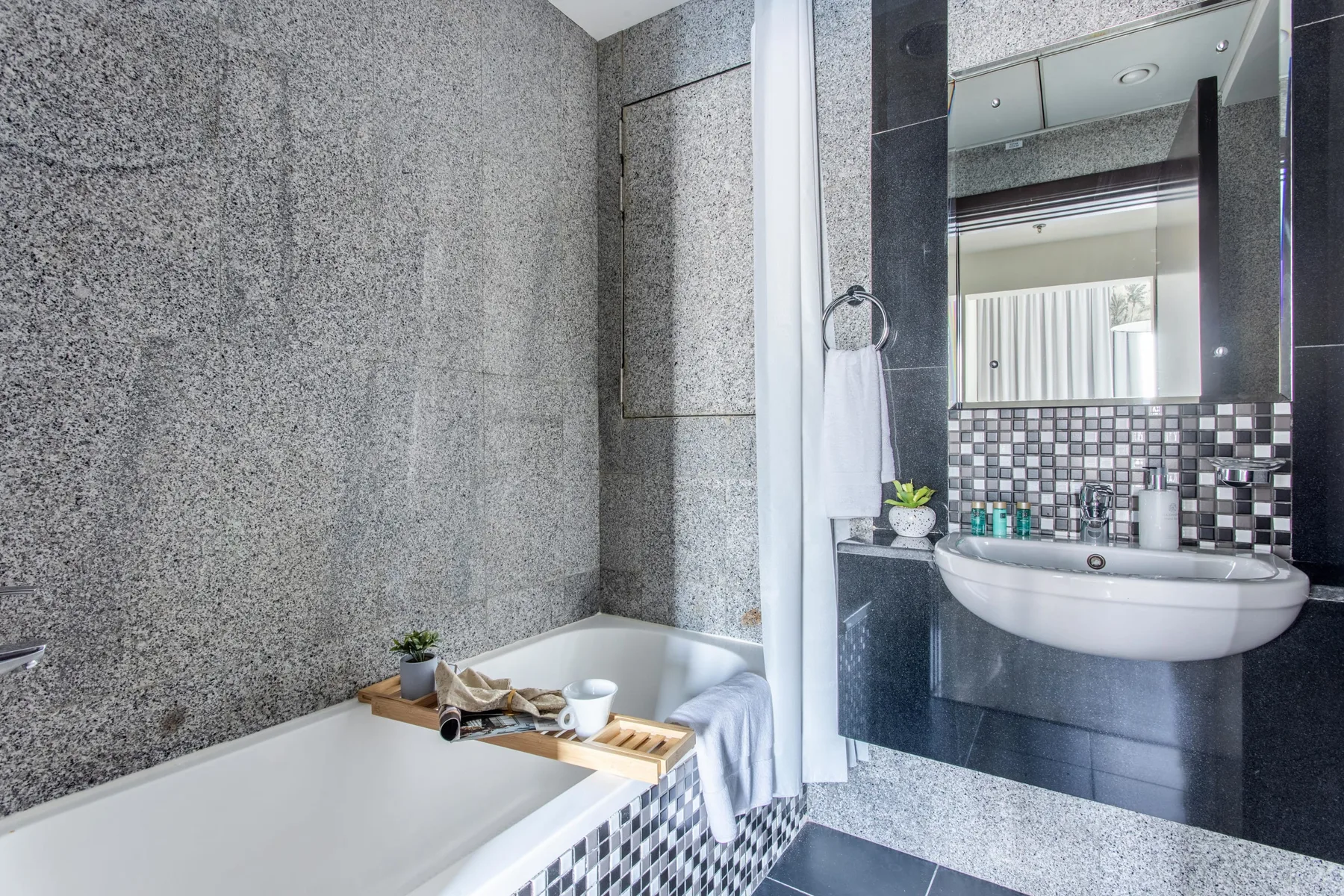 A bathroom with a bathtub and a sink beneath a mirror.