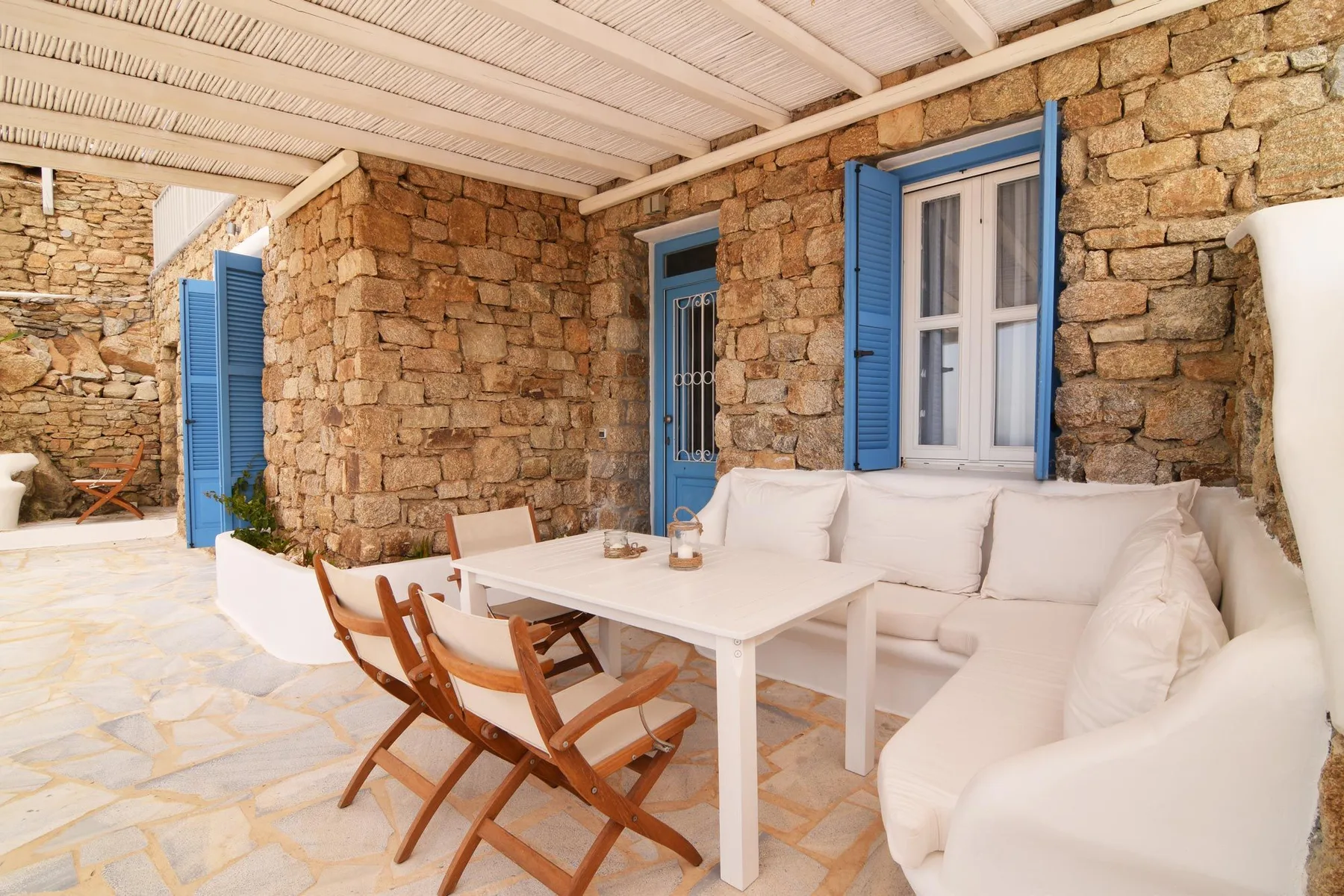 A stone-walled patio has a white outdoor seating area and table.