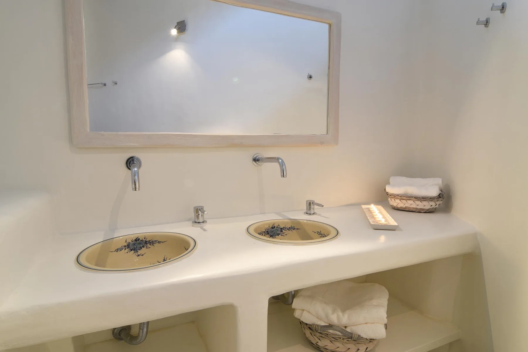 A bathroom vanity with two sinks, a mirror, and folded towels.