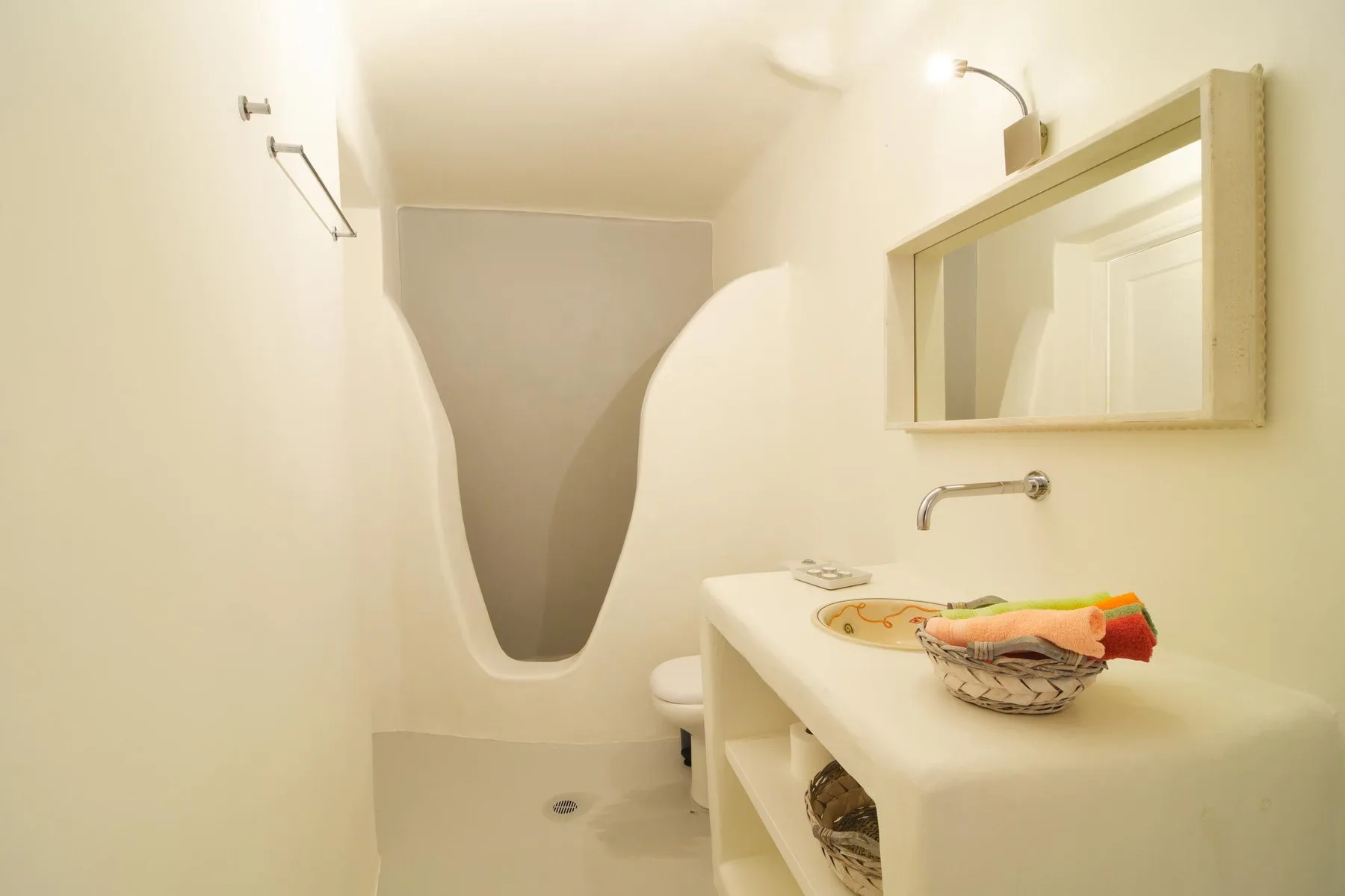 A bathroom with a curved shower alcove and a long white sink counter.