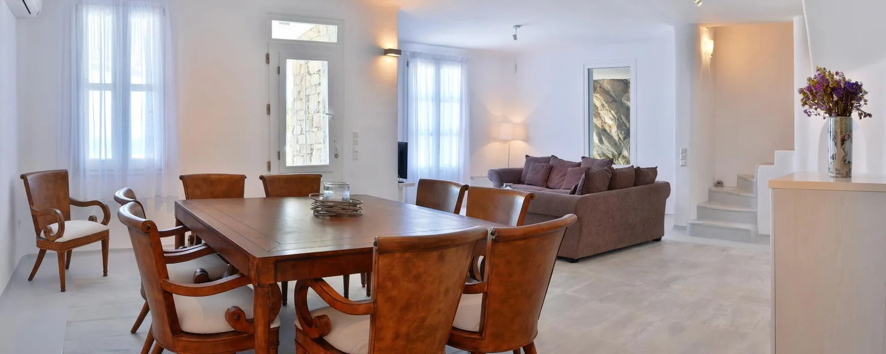 A bright dining and living area with a wooden dining table and seating.