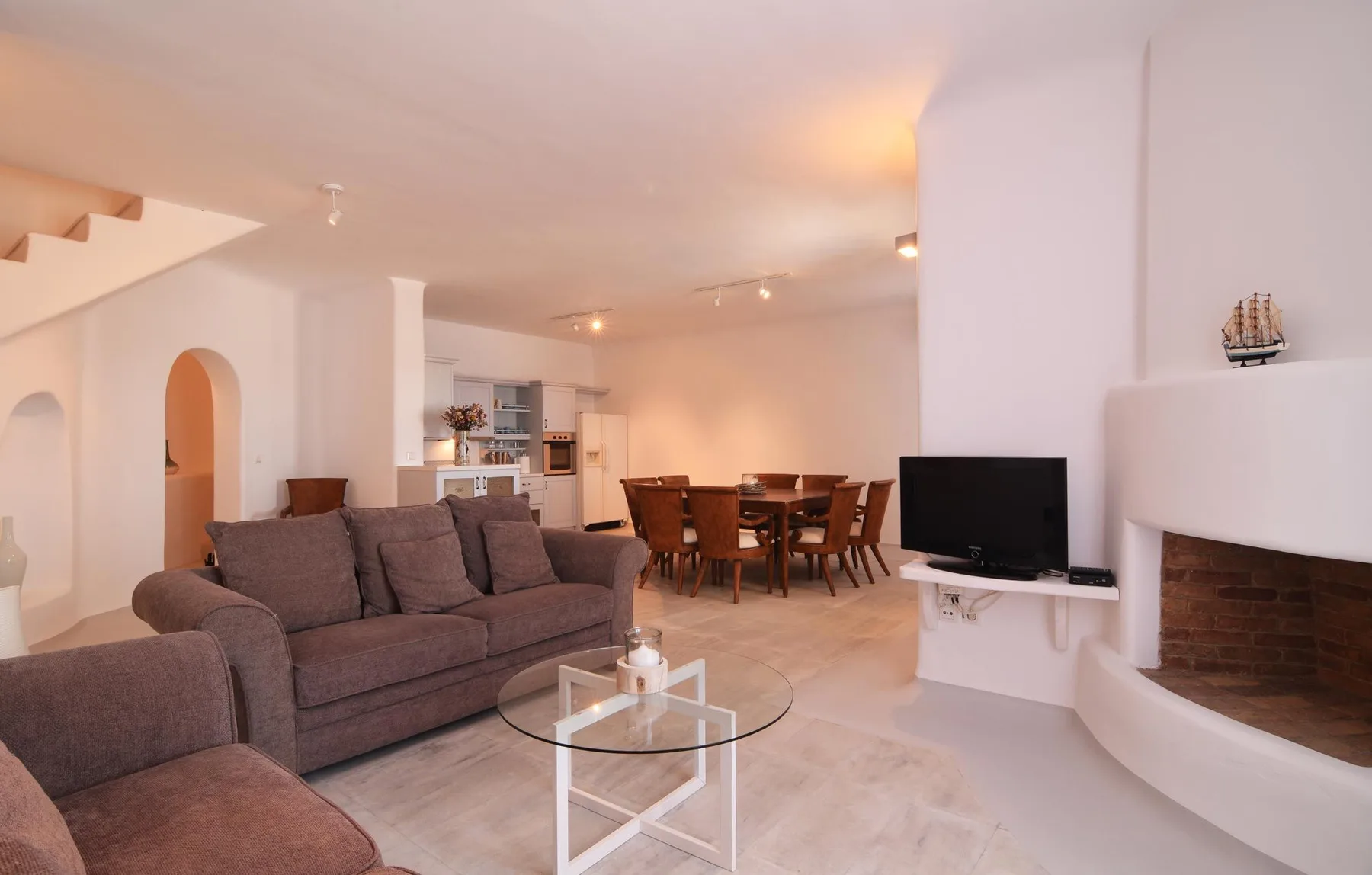 A bright living and dining area with seating, a television, and a dining table.