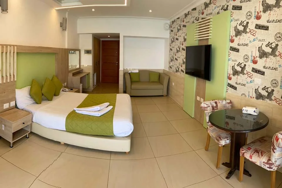 Espacio representativo del hotel: Una habitación de hotel con cama, un sofá pequeño y un televisor.